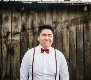 Tim Thao standing in front of a wooden fence